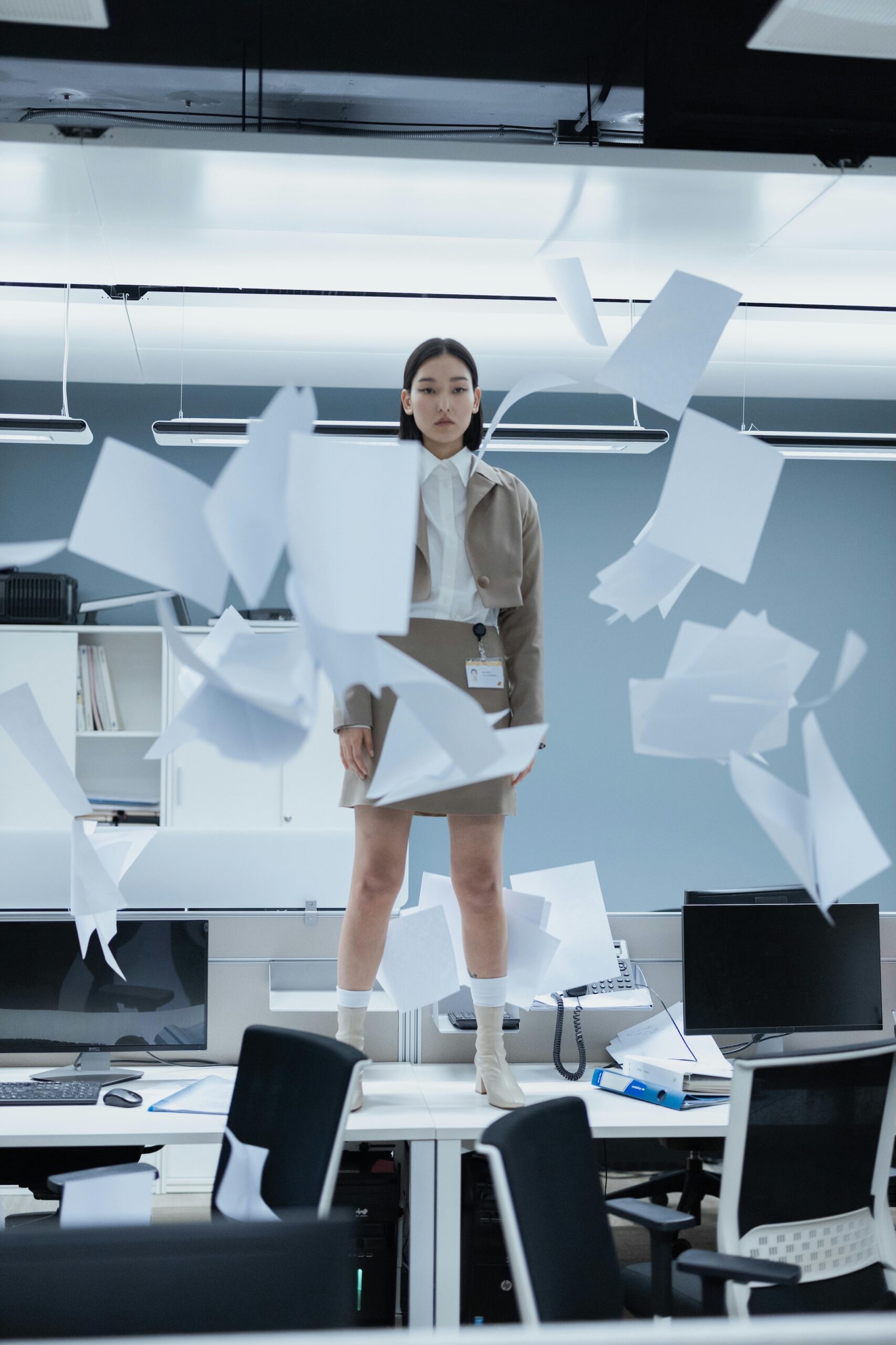 Woman standing on desk, papers flying